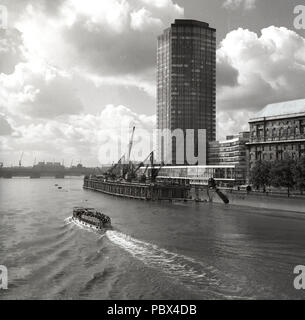 Anni sessanta, storico, un battello da diporto va giù il fiume Tamigi presso il ponte di Cleveland imbarcadero o piattaforma galleggiante, accanto a una nuova costruzione alto e moderno edificio di uffici a Londra, Inghilterra, Regno Unito. Il 60s ha visto la riva del tamigi cambiare per sempre come pontili furono sviluppate in blocchi a torre e l'alloggiamento. Foto Stock