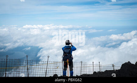 Scalatore guardando sopra le nuvole dalla cima del monte Fuji in Giappone Foto Stock Scalatore guardando sopra le nuvole dalla cima del monte Fuji in Giappone Foto Stock