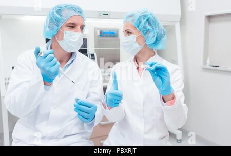 Gli scienziati in Biotech Lab con pipetta e il piatto del campione Foto Stock