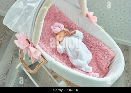 Carino neonato ragazza con la mano in bocca. La ninna nanna Mosè cestello. Foto Stock