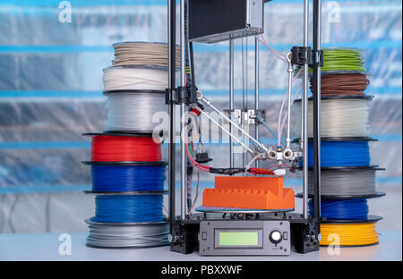 ABS e PLA filament accanto alla stampante 3D. Bobine di plastica Foto Stock
