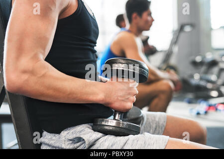 Irriconoscibile giovani fit men in palestra esercizio con manubri. Foto Stock