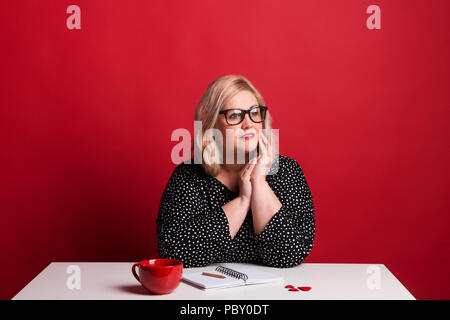 Ritratto di un attraente Donna sovrappeso in studio su uno sfondo di colore rosso. Foto Stock