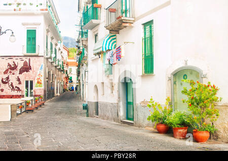 Strada stretta nella piccola città italiana famosa per la sua decorazione ceramica su pareti con vasi di fiori e la biancheria appesa sul balcone Foto Stock