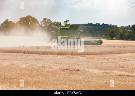 Earls Barton, Northamptonshire, Regno Unito. 26 Luglio, 2018. Un campo al di fuori di Earls Barton rd con un John Deere HillMaster S785i mietitrebbia facendo la maggior parte Foto Stock