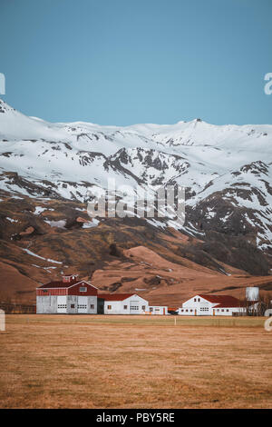 Tipico paesaggio islandese con case bianco rosso tetto contro le montagne del piccolo villaggio nel sud dell'Islanda. Foto Stock