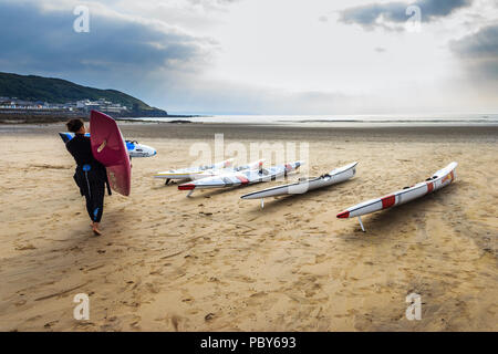 Surfista femmina con bordo, surf e sci racing Canoe sulla spiaggia di Condino, Devon, Regno Unito Foto Stock