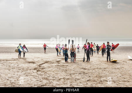 Un grande gruppo di surfers, surf sciatori e kayakers incontro sulla spiaggia di Condino, Devon, Regno Unito Foto Stock