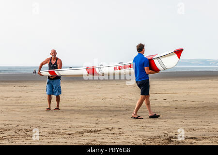 Due uomini che trasportano un Gaisford Bladerunner doppia sci di surf sulla spiaggia di Condino, Devon, Regno Unito Foto Stock