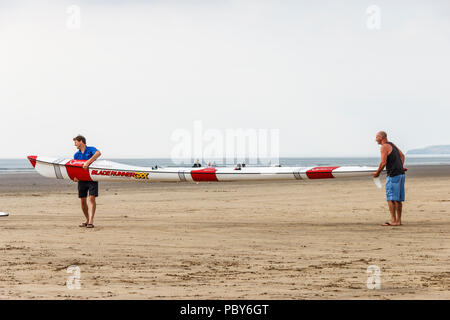 Due uomini che trasportano un Gaisford Bladerunner doppia sci di surf sulla spiaggia di Condino, Devon, Regno Unito Foto Stock