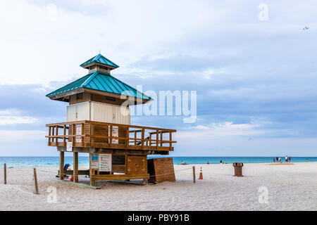 Sunny Isles Beach, Stati Uniti d'America - 7 Maggio 2018: Lifeguard edificio lungo la costa dell'oceano a Miami in Florida sera, la gente camminare sulla sabbia durante il tramonto Foto Stock