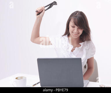 Giovane donna di affari con una pinza, per colpire il computer portatile. Foto Stock