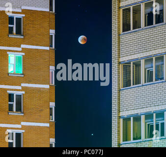 Eclissi di luna in luna piena. Super sangue blu moon in luglio 27, 2018 la Bielorussia. Paesaggio urbano: facciata di un edificio a più piani contro lo sfondo della Foto Stock