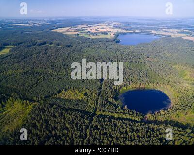 Vista aerea del bellissimo paesaggio della regione Mazury, piccolo lago in un bosco vicino a Ogonki, Lemiet Lago sullo sfondo, Polonia Foto Stock