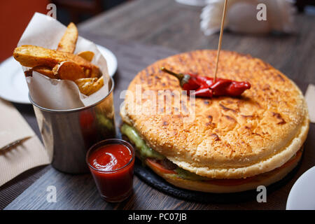 Golden Spicchi di patate con big burger sul tavolo Foto Stock