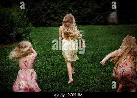 La comparsa di tre piccoli ragazze vestito con un abito in esecuzione nel parco Foto Stock