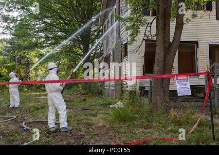 Detroit, Michigan - uso abbigliamento protettivo per la protezione contro l'esposizione all'amianto, lavoratori preparare per la demolizione di una casa abbandonata. Essi spruzzare acqua sul Foto Stock