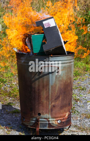 La combustione dei rifiuti di carta e cartone in un piccolo giardino inceneritore Foto Stock