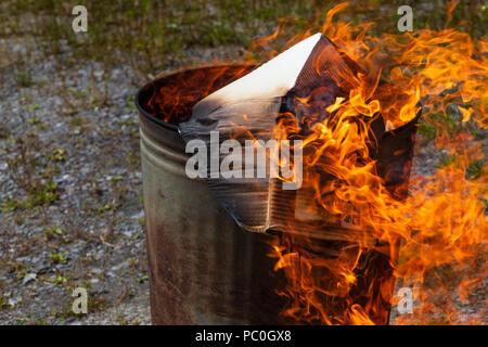 La combustione dei rifiuti di carta e cartone in un piccolo giardino inceneritore Foto Stock