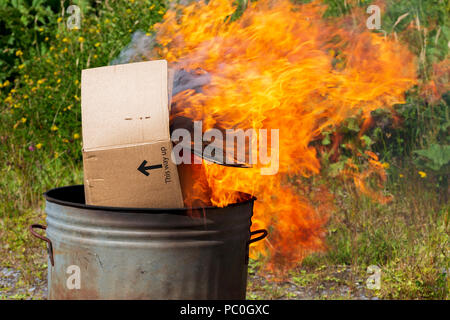 La combustione dei rifiuti di carta e cartone in un piccolo giardino inceneritore Foto Stock