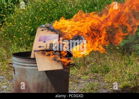 La combustione dei rifiuti di carta e cartone in un piccolo giardino inceneritore Foto Stock