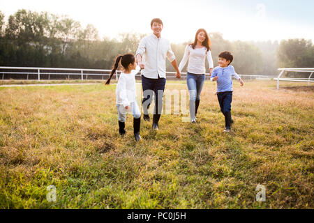 Allegro giovane famiglia cinese camminando sul campo erboso Foto Stock