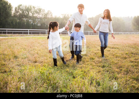 Allegro giovane famiglia cinese camminando sul campo erboso Foto Stock
