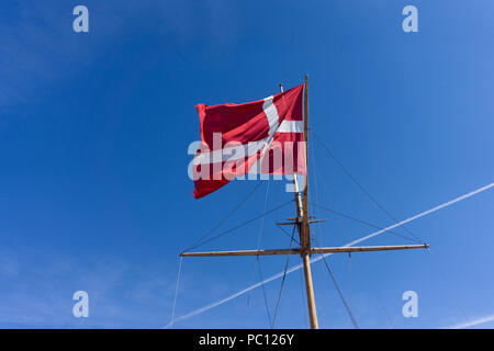 Bandiera della Danimarca su un montante di nave waivng contro un cielo blu chiaro Foto Stock