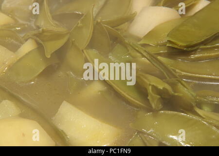 Baccelli di piselli e patate essendo realizzati in zuppa Foto Stock