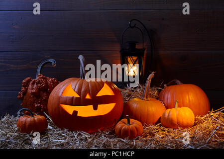 Intagliato jack zucca lanterna e zucche in dark barn, Halloween holiday celebrazione concept Foto Stock