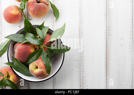 Pesche fresche i frutti con foglie di colore bianco su sfondo di legno, vista dall'alto Foto Stock