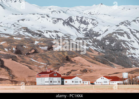 Tipico paesaggio islandese con case bianco rosso tetto contro le montagne del piccolo villaggio nel sud dell'Islanda. Foto Stock