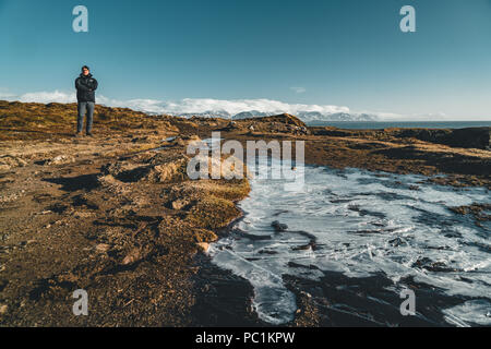 Arnarstapi , Islanda - Maggio 2018: giovane maschio permanente turistico nei pressi di un piccolo ghiacciaio in una bella giornata con il bue sky. Foto Stock