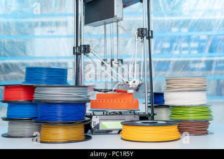 ABS e PLA filament accanto alla stampante 3D. Bobine di plastica Foto Stock