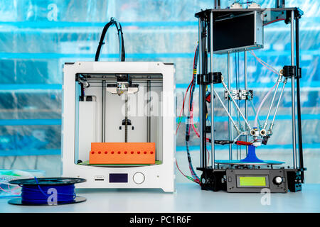ABS e PLA filament accanto alla stampante 3D. Bobine di plastica Foto Stock