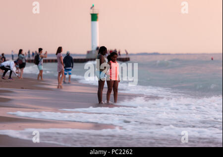 La visione di un tramonto mozzafiato iniziano a slittare sotto la horizion mentre le persone si radunano sulla spiaggia di Grand Bend. Foto Stock