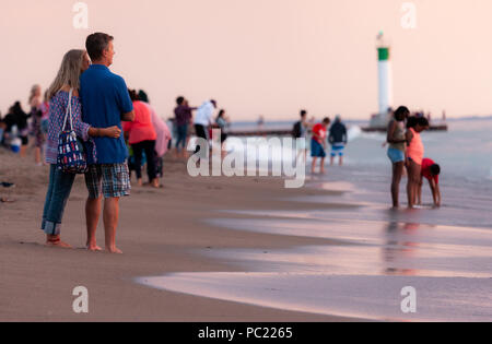 La visione di un tramonto mozzafiato iniziano a slittare sotto la horizion mentre le persone si radunano sulla spiaggia di Grand Bend. Foto Stock