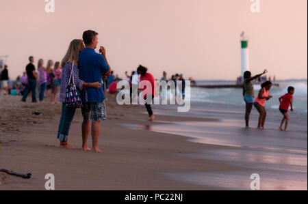 La visione di un tramonto mozzafiato iniziano a slittare sotto la horizion mentre le persone si radunano sulla spiaggia di Grand Bend. Foto Stock