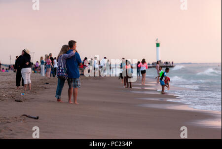 La visione di un tramonto mozzafiato iniziano a slittare sotto la horizion mentre le persone si radunano sulla spiaggia di Grand Bend. Foto Stock