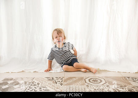 Urlando piccolo ragazzo sul pavimento Foto Stock