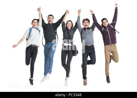 Allegro all'estero studenti holding hands jumping Foto Stock