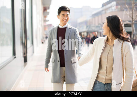 Allegro giovani cinesi giovane tenendo le mani a piedi Foto Stock