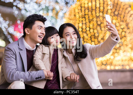 Allegro giovane famiglia cinese tenendo autoritratto con smart phone Foto Stock