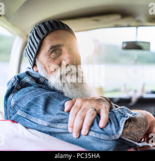 Ritratto di un vecchio hipster seduto in un furgone guardando la fotocamera Foto Stock