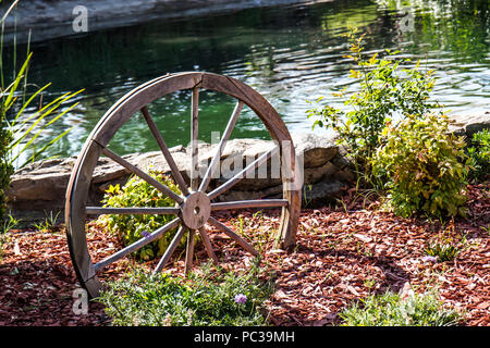 Legno Ruota di carro sepolto in terra accanto al laghetto Foto Stock