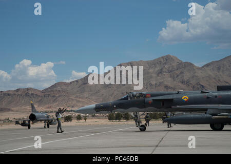 Un colombiano Air Force Kfir fighter jet capo equipaggio segnali per un pilota mentre un altro colombiano Kfir fighter jet taxi sulla linea volo prima di un lancio per Red Flag 18-3 presso la Base Aerea Militare di Nellis Nev., 24 luglio 2018. Questa è la seconda volta il colombiano Air Force ha partecipato alla bandiera rossa esercizio; che precedentemente hanno partecipato nel 2012. (U.S. Air Force photo by Staff Sgt. Angela Ruiz) Foto Stock