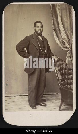 African American uomo, eventualmente denominato 'Small', a piena lunghezza ritratto in studio, ben vestito, in piedi, rivolto verso la parte anteriore con la mano sinistra appoggiata sul retro di una sedia) Foto Stock