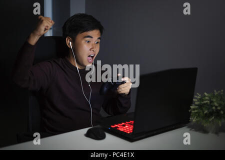Felice giovane utilizzando il joystick per giocare Foto Stock