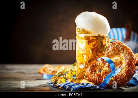 Boccali da birra e salatini su un tavolo di legno. Oktoberfest. Festa della birra. Foto Stock