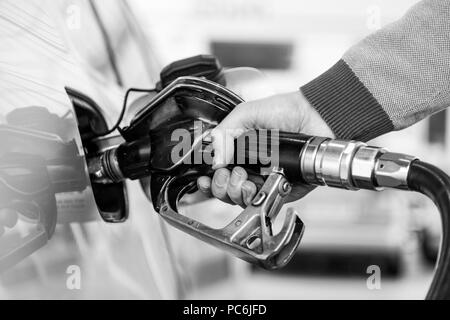 Primo piano della mano mans pompando benzina in auto alla stazione di gas. Foto Stock